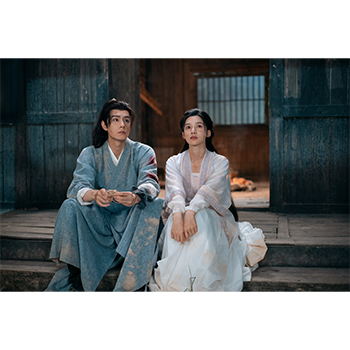 戸口に並んで座る2人の場面写真。特定の収録話数をこの画像だけで判断しないでください。